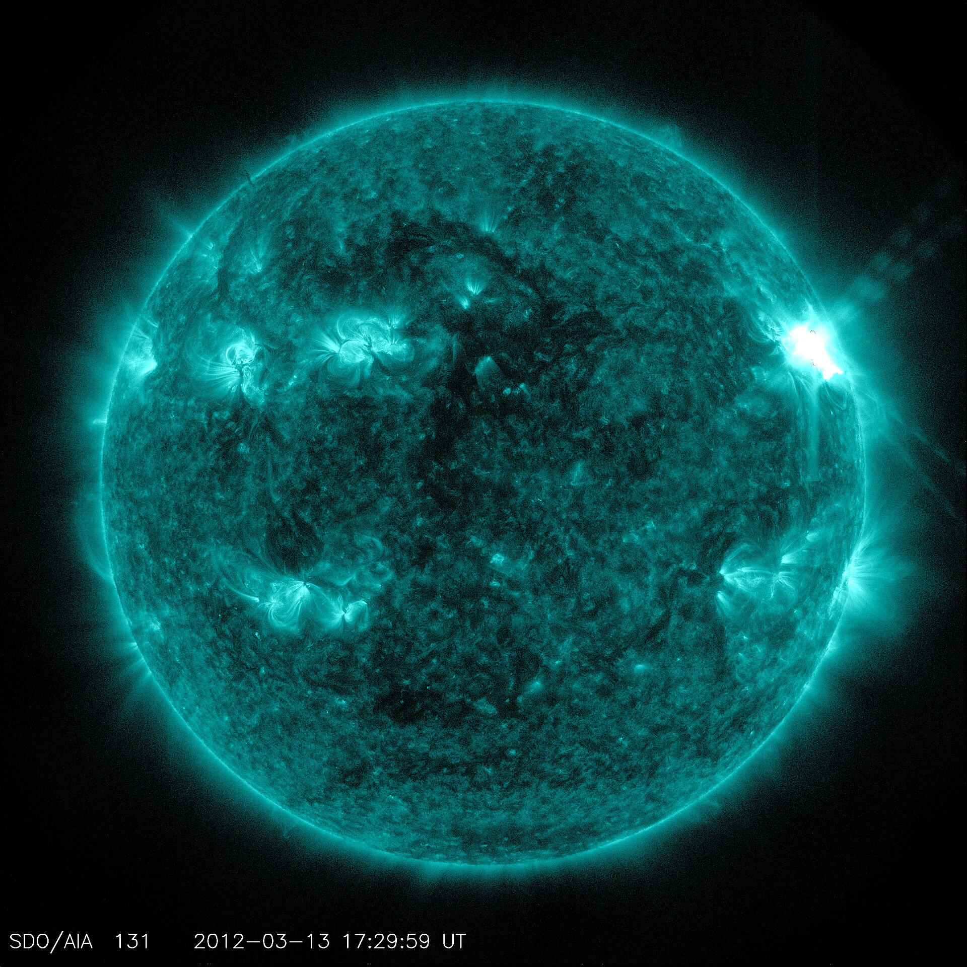 A bright solar flare erupting above a sunspot region, seen in extreme ultraviolet light